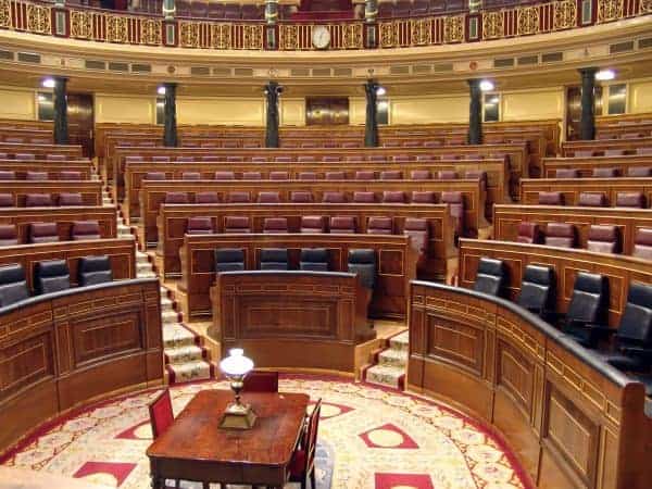 Hemiciclo del Congreso de los Diputados con bancadas de madera, marquetería y tapicería histórica.